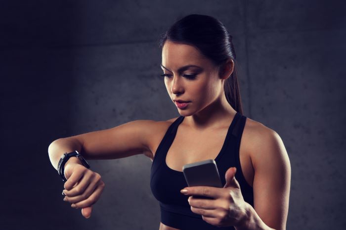 Mujer utiliza sus dispositivos móviles para hacer ejercicios.